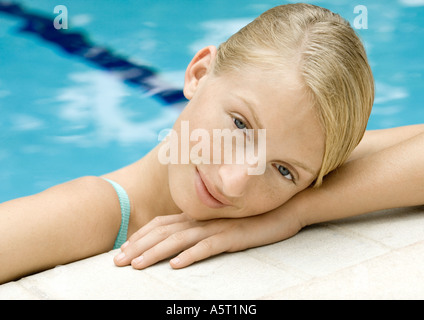 Mujer joven cabeza descansando sobre el borde de la piscina Foto de stock