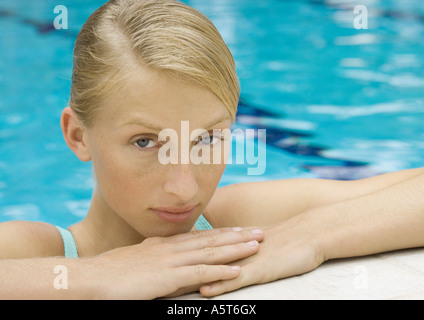 Mujer joven descansando sobre el borde de la piscina, close-up Foto de stock