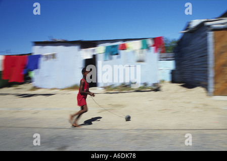 Un niño pasa por delante de la choza típica en Khayelitsha Township, Ciudad del Cabo, Sudáfrica Foto de stock