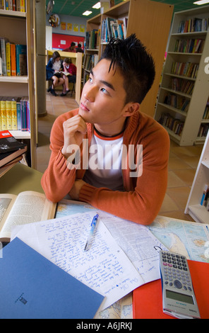 Oriental coreano escuela de adolescentes varones entre 15 y 17 años de estudiante en el pensamiento profundo y la contemplación con su examen de la biblioteca de la escuela de estudios Foto de stock