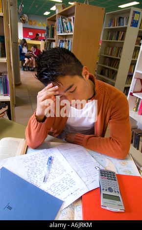 Korean senior estudiante adolescentes 15-17 años estudiando y pensando atentamente en la biblioteca escolar para revisiones de examen Foto de stock