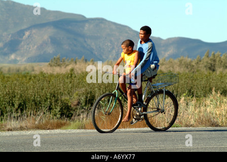 Dos chicos en bicicleta con rueda desinflada ciclismo Western Cape Sudáfrica RSA Foto de stock