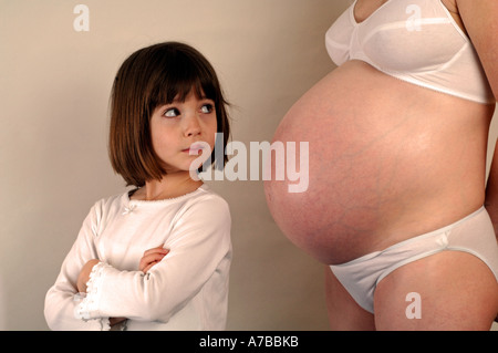 Mujer embarazada con celosa hija mirando su estómago Foto de stock
