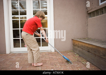 Niño de ocho años barriendo el patio Fotografía de stock - Alamy