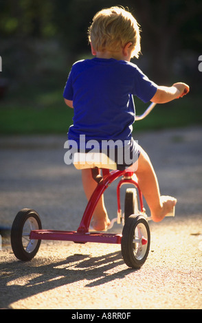 Niño de tres años montando triciclo Foto de stock