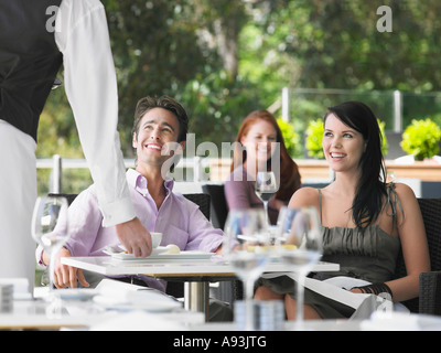 Camarero trayendo café para pareja en el café al aire libre