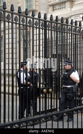 Tres policías uniformados guardias, dos dentro y uno fuera de puertas principales a Downing Street, Londres, Inglaterra, Reino Unido. Foto de stock