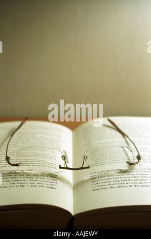 Un par de gafas sin reborde tumbado sobre un libro abierto Foto de stock