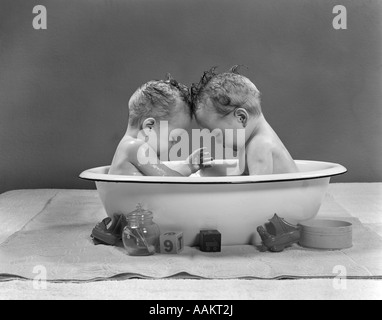 1950 TWIN BEBÉS sentados frente a frente en bañera metálica