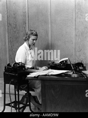 1930 MUJER SECRETARIA EN OFICINA COMERCIAL cubierta la transcripción de la grabación de voz de dictado DICTAFONO MÁQUINA Foto de stock