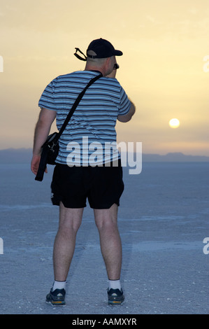 Turista masculina en pantalones cortos y gorra de béisbol toma el metraje de vídeo de la salida del sol sobre chott el djerid Túnez Foto de stock