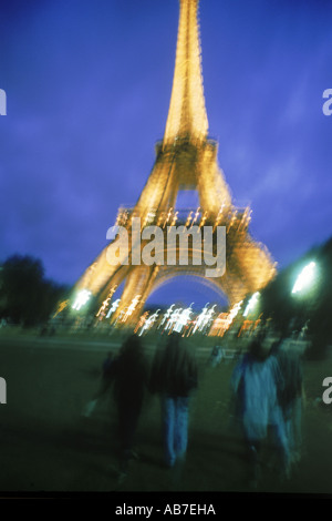 Vista trasera de parejas caminando hacia la Torre Eiffel por la noche Foto de stock