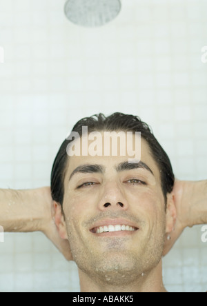 Hombre sonriendo con las manos detrás de la cabeza en la ducha Foto de stock