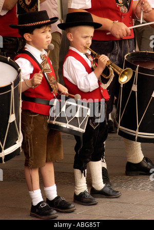 Niños vestidos con traje folclórico tradicional bávaro jugar con una banda local en Munich Alemania, junio de 2006