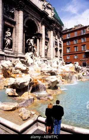Par los turistas echando monedas a la famosa Fuente de Trevi para volver a Roma Roma Italia Foto de stock