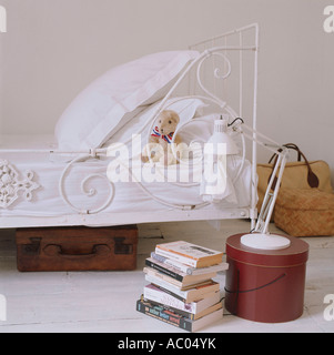 Antiguos niños de la cama de hierro forjado con el libro montón y equipaje viejo Foto de stock