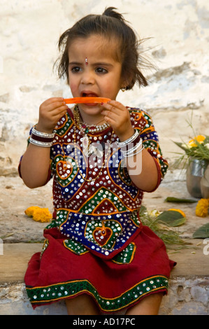Vertical cerca de una bonita niña india comiendo una máquina de paleta de helado con su mejor vestido en el Festival Ugadi Foto de stock