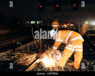 Personal de mantenimiento ferroviario realizando trabajos de mantenimiento en vías ferroviarias por la noche en el Reino Unido. Foto de stock