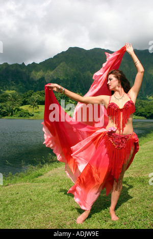 Bailarina de danza del vientre con velo rojo los brazos extendidos en un  escenario tropical Fotografía de stock - Alamy