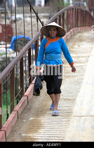 Zay mujer en ropa tradicional sombrero cónico y cruza el puente Ta Van aldea cerca de Sapa Vietnam del norte Foto de stock