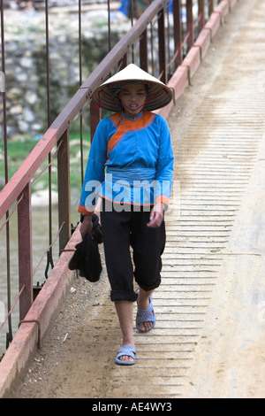 Zay mujer en ropa tradicional sombrero cónico y cruza el puente Ta Van aldea cerca de Sapa Vietnam del norte Foto de stock