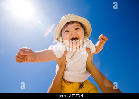 Manos sosteniendo bebé (6-9 meses) en aire, Retrato Foto de stock