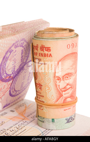 Rollo de rupias indias en un pasaporte británico con un indio de Visa. Aislado en blanco. Foto de stock