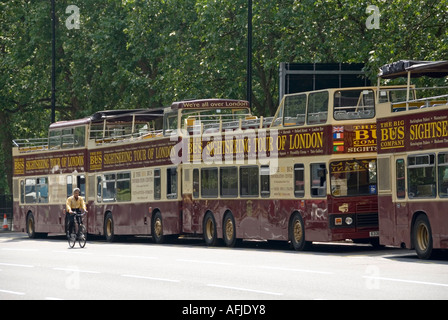 Los autobuses turísticos grandes aparcados al lado de Hyde Park esperan ser llamados a la parada de autobús en Marble Arch pasando por el ciclista Inglaterra Reino Unido Foto de stock