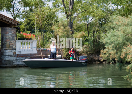 Hombre y niño en pequeñas lanchas de pesca en el canal de la isla de Torcello Italia