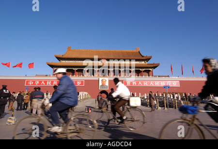Los ciclistas ir en frente del retrato de Mao en la plaza de Tiananmen en Pekín, China Foto de stock