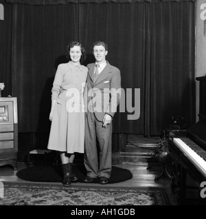 VINTAGE vieja fotografía familiar snap shot PAREJA DE PIE EN EL SALÓN CON PIANO Y ANTIGUA RADIO circa 1950