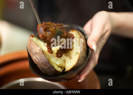 Chaqueta de Mujer persona sirviendo cocido patatas o patata dulce alimento  poniendo en atún mayonesa llenando con cuchara Fotografía de stock - Alamy