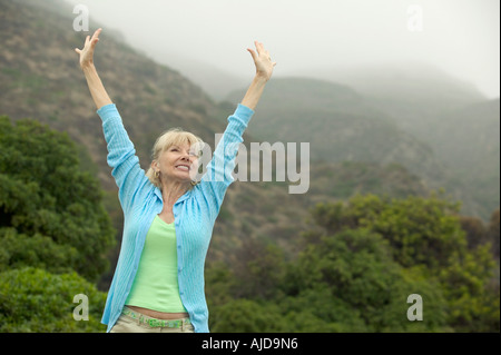 Mujer elevando los brazos cerca de forest Foto de stock