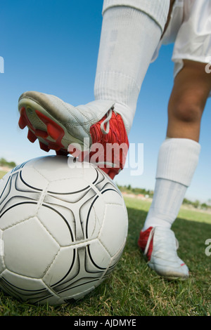 Jugador de fútbol (13-17) de pie sobre la bola, bajo la sección
