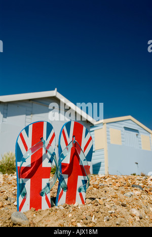 Par de flip flops en Pebble Beach con cabañas de playa en St Leonards antecedentes sobre mar Hastings Sussex England GB Foto de stock