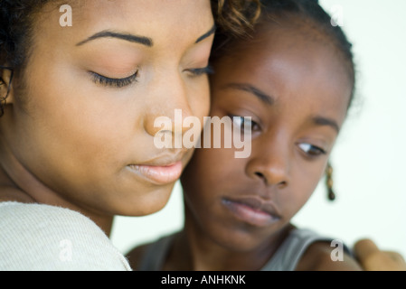 Madre e hija, en la mejilla a la mejilla, tanto mirando hacia abajo, close-up