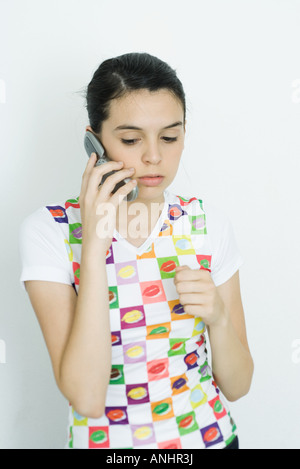 Adolescente sosteniendo un teléfono celular, mirando hacia abajo