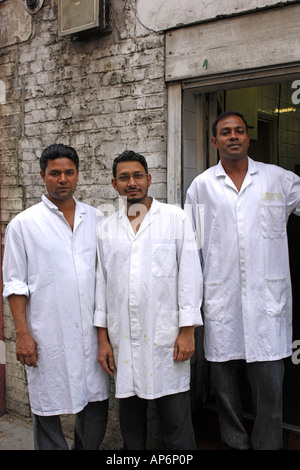 Tres hombres asiáticos vistiendo batas fuera carnicería Halal tienda en Brick Lane Londres Fotografía de stock - Alamy