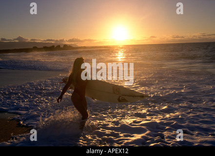 Mujer en traje de baño con tablas de surf en el Waters Edge Foto de stock