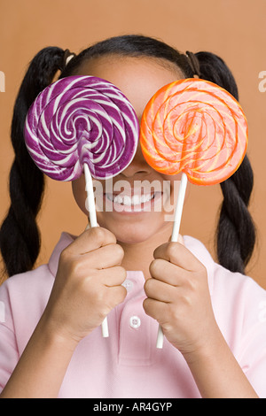 Chica sujetando lollipops a través de sus ojos Foto de stock