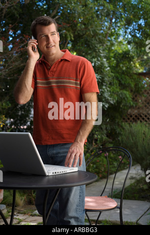 Hombre en el patio con teléfono móvil y el ordenador Foto de stock