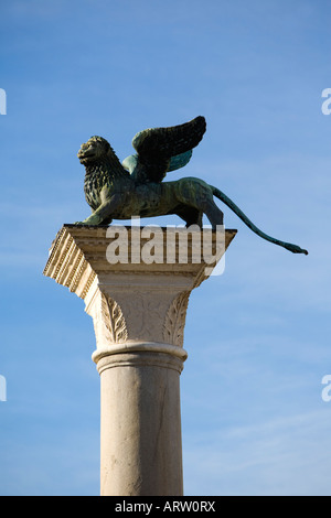 El león alado, símbolo de Venecia (Italia) se asienta sobre una columna en la entrada a la Plaza de San Marcos. Foto de stock