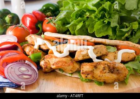 https://l450v.alamy.com/450ves/at4rft/un-fresco-shish-kebab-de-pollo-caliente-servido-en-un-plato-de-madera-en-un-pan-de-pita-con-ensalada-y-mayonesa-at4rft.jpg