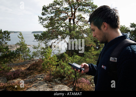 Excursionista macho verificando el curso con el receptor de GPS en la costa sueca Stockholms Lan Bjorno Septiembre 2007 Foto de stock