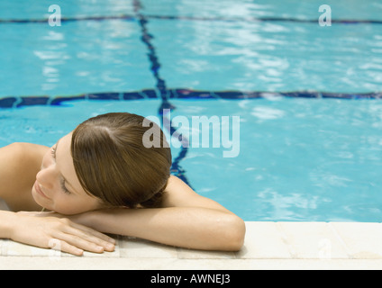 Mujer joven cabeza descansando en el lado de la piscina Foto de stock