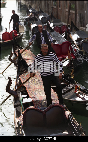 3 del gondolero remando hacia abajo un canal en una góndola punto de recogida en San Marcos, al oeste de la plaza de San Marcos Venecia Foto de stock
