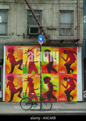 Coloridos carteles publicitarios en frente de la pared gris de la casa con escalera de incendios, ESTADOS UNIDOS, Manhattan, Nueva York Foto de stock