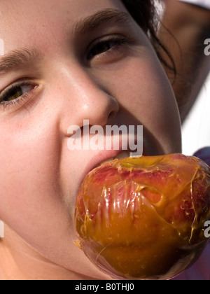 Muchacha comiendo manzanas de caramelo Foto de stock