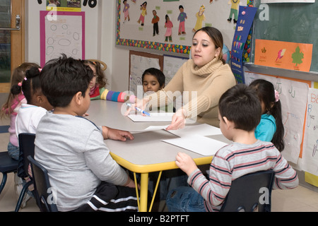 Maestra de preescolar y sus estudiantes en una mesa para colorear Foto de stock