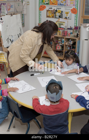 Maestra de preescolar y sus estudiantes en una mesa para colorear Foto de stock